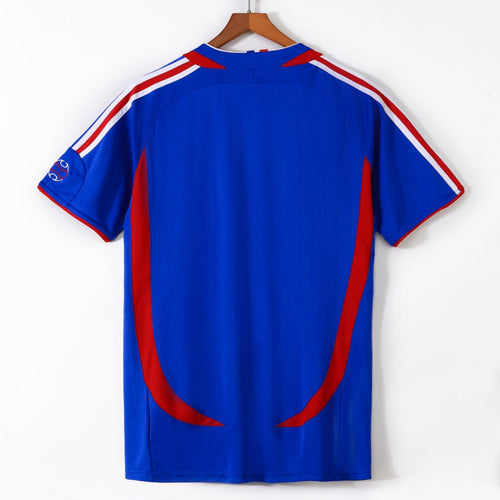 Maillot rétro domicile France 2006, marque Le 12-ème Maillot, vue de face avec logo et détails bleus et rouges sur fond blanc.