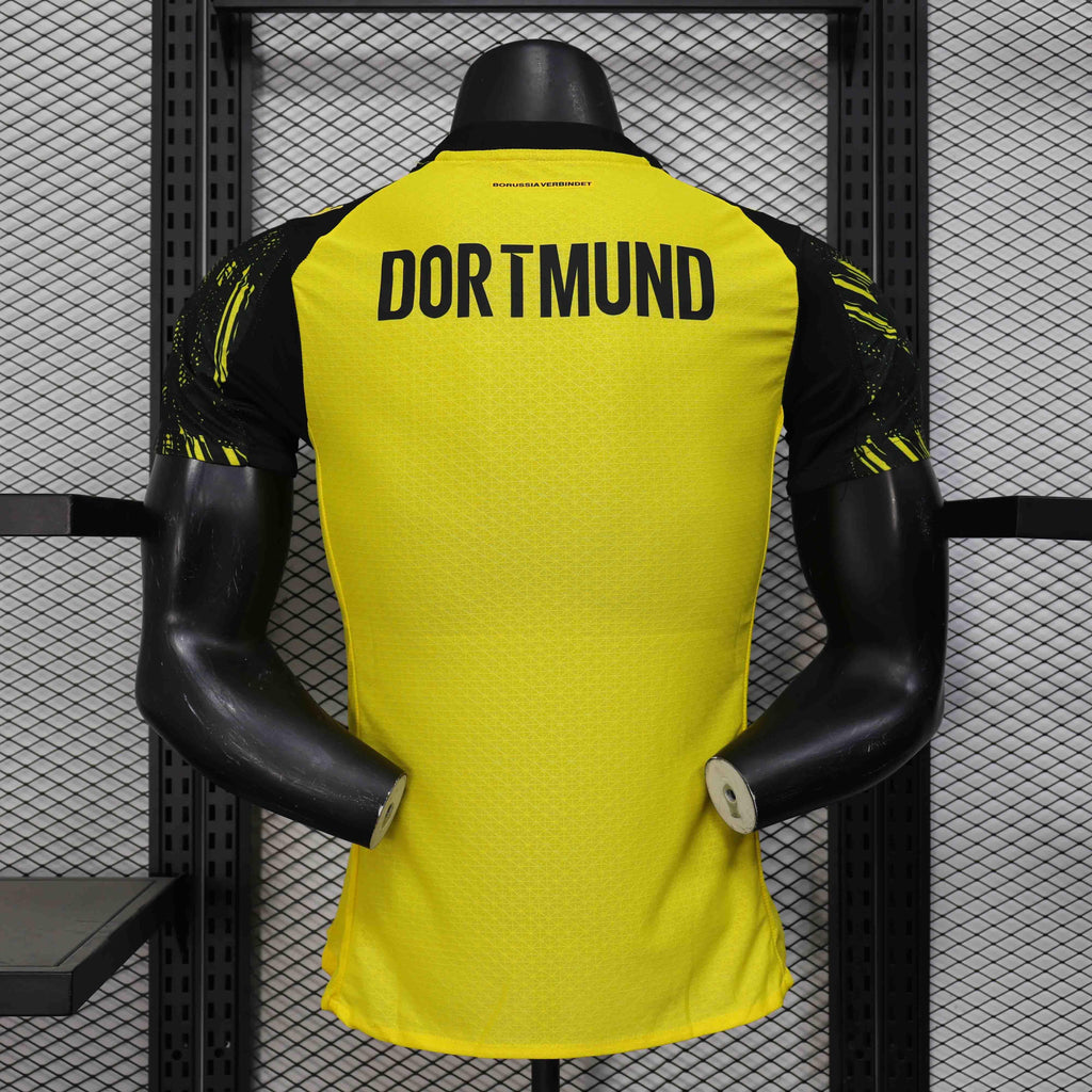 Maillot Dortmund 25-26 Le 12 -ème Maillot, maillot de football noir avec logo et détails dorés, vue de face.