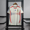 Maillot rétro de l'équipe de France 2006, marque Le 12 -ème Maillot, vue de face avec logo et design bleu et blanc.