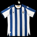 Maillot domicile 25/26 de la Real Sociedad, marque Le 12-ème Maillot, vue de face avec logo et détails de l'équipe.
