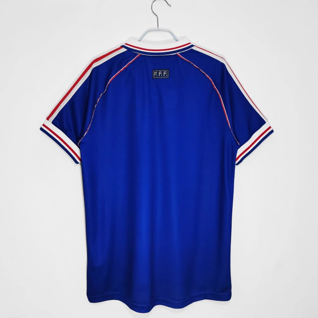 Maillot rétro de l'équipe de France 1998, marque Le 12 -ème Maillot, avec logo et design authentique visible sur le vêtement.