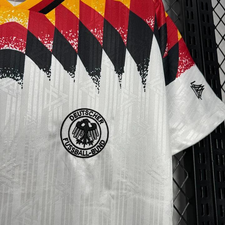 Maillot rétro de l'Allemagne 1994 par Le 12 -ème Maillot, vue de face, tissu blanc avec détails noirs et logo officiel.